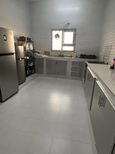 a kitchen with a white tiled floor and appliances at إستراحة حجيف فيو in Salalah