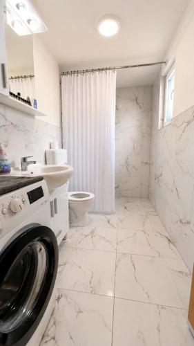 a white bathroom with a washing machine in it at Apaurin Lodge - Peacful Nature Escape near Bosnian Pyramids in Visoko