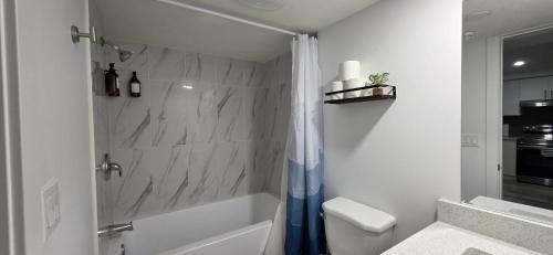 a white bathroom with a shower and a toilet at Entire guest basement suite in Cochrane, AB in Cochrane