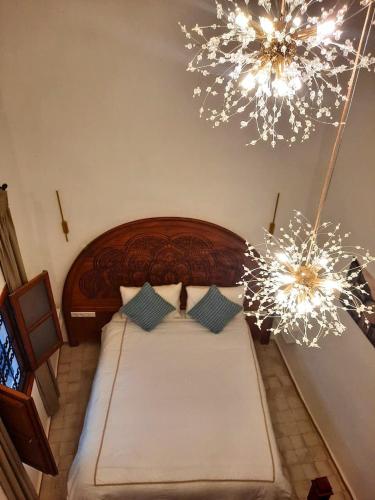 a bedroom with a large bed with two chandeliers at Dar Al Massir in Chefchaouen