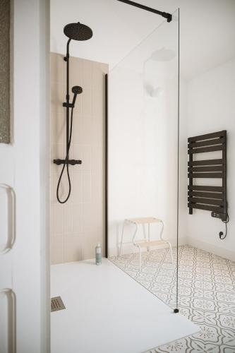 a white bathroom with a shower and a chair at L'Annexe Singulière in Maillé