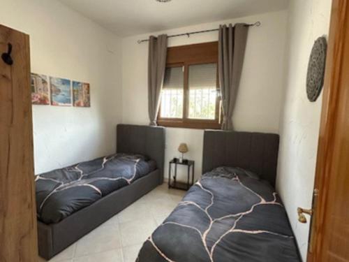 a bedroom with two beds and a window at Vila Girasoles in Cálig