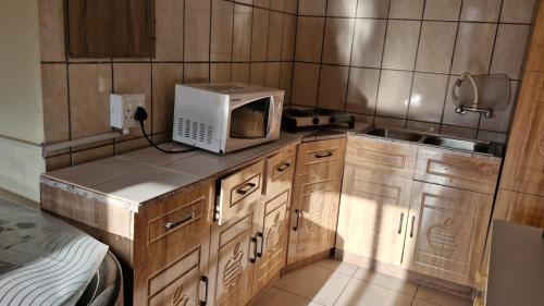 a small kitchen with a microwave and a sink at Self Contained Batchelor pad in Germiston