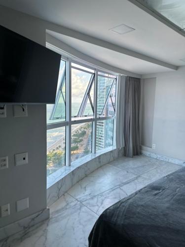 a bedroom with a bed and a large window at Hotel Beira Mar Boa Viagem By Flatbpaiva in Recife