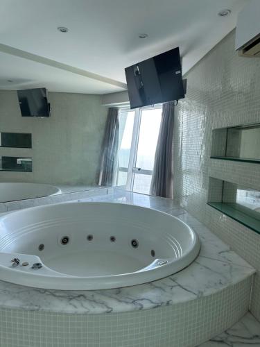 a large white bath tub in a bathroom at Hotel Beira Mar Boa Viagem By Flatbpaiva in Recife
