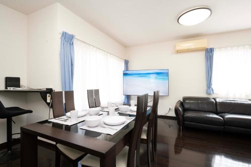 a dining room with a table and a leather couch at Shiokaze Miura Kaigan - 三浦海岸 in Miura