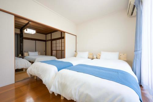 a bedroom with two large beds with blue sheets at Shiokaze Miura Kaigan - 三浦海岸 in Miura