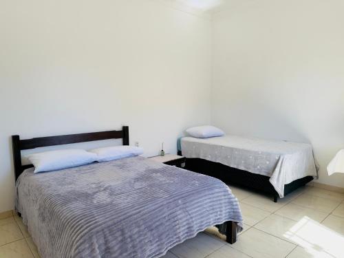 a bedroom with two beds and a white wall at Apartamento com 2 quartos, 2 banheiros e Garagem em sinop in Sinop
