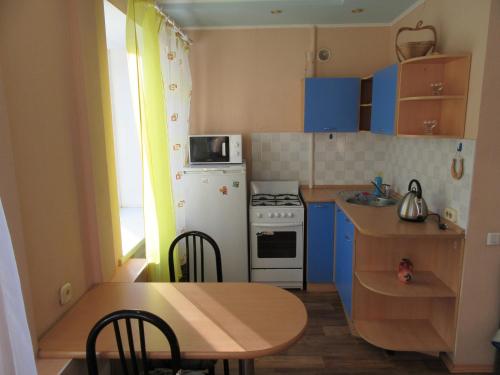 ペルミにあるApartments on Krasnovaの小さなキッチン(テーブル、白い冷蔵庫付)