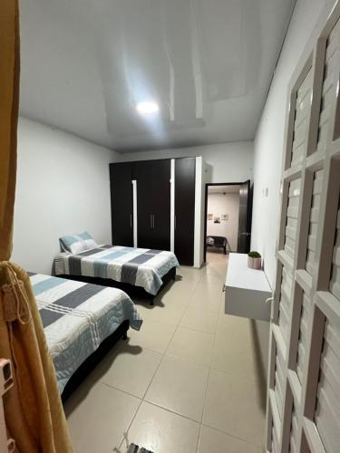 a bedroom with two beds and a room with two tables at Casa de Libre Independencia in Mocoa