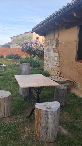 a picnic table with three logs and a building at Casa eclipse in Padilla de Abajo