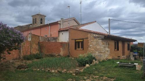an old brick building with a church in the background at Casa eclipse in Padilla de Abajo
