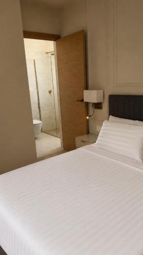 a bedroom with a large white bed and a bathroom at Malaga Rooms in Málaga