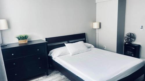 a bedroom with a bed with a black dresser and white sheets at Wasaga Daze - Unit B in Wasaga Beach