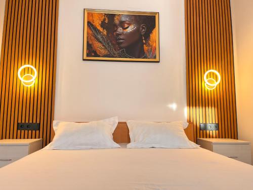 a bedroom with a bed with two lamps and a picture on the wall at Casa Alba - Tasnad in Tăşnad