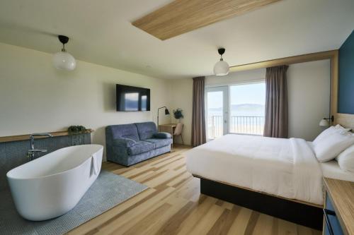 a bedroom with a large bed and a bath tub at BATTURES Hotel Fjord Saguenay in La Baie
