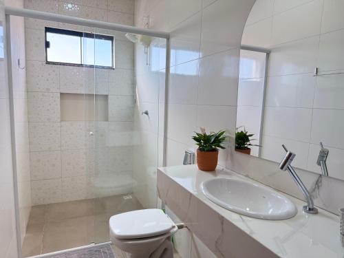 a white bathroom with a toilet and a sink at Apartamento com 2 quartos próximo do centro in Sinop