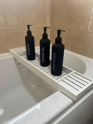 three black bottles sitting on a shelf on a bath tub at Large river side house, parking,for 9 people in Bedford