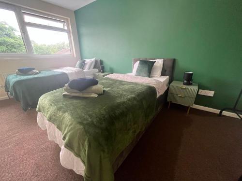 two beds in a room with green walls and a window at Large river side house, parking,for 9 people in Bedford