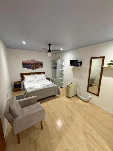 a bedroom with a bed and a couch and a mirror at kitnet Residencial Ozzy com Garagem Coberta em Betim in Betim