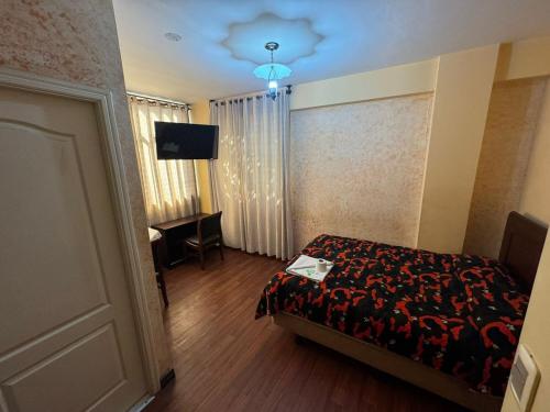 a bedroom with a bed and a desk and a television at Hotel Savoy in La Paz