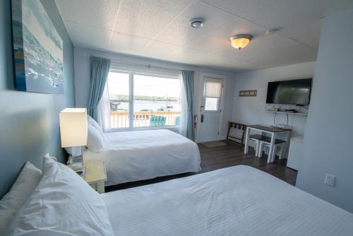 a hotel room with two beds and a window at Silver Lining Inn and Motel in Chéticamp