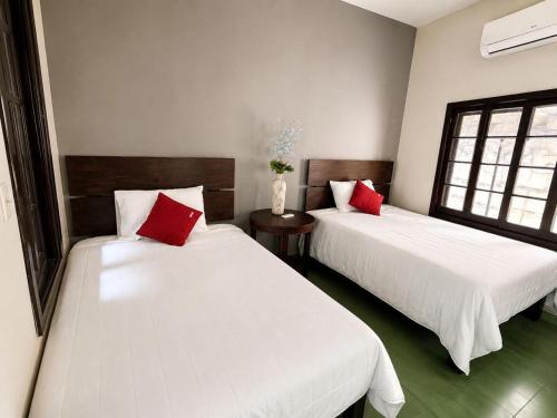 two beds with red pillows in a room at Hotel Puerta de Jade in Ciudad Valles
