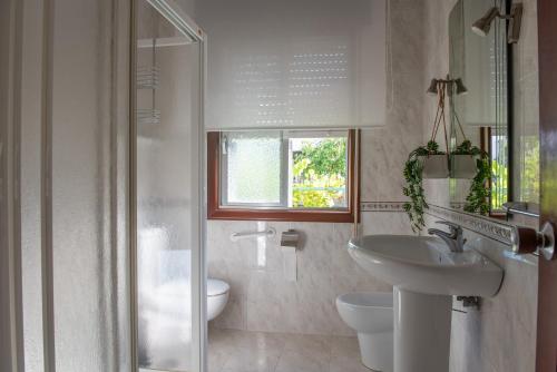 a bathroom with a sink and a toilet and a window at Laxes do Mar in Baiona