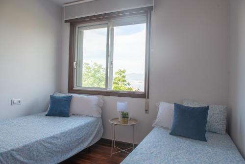 a bedroom with two beds and a window at Laxes do Mar in Baiona