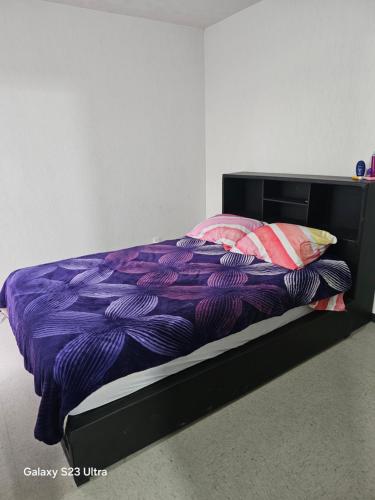 a bed with a purple comforter and pillows at La comodidad a tu alcance in Bata