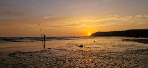 a person standing on the beach with a fishing pole at appart villa galactik pegasus in Aourir