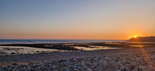 a sunset on a beach with a lot of rocks at appart villa galactik pegasus in Aourir