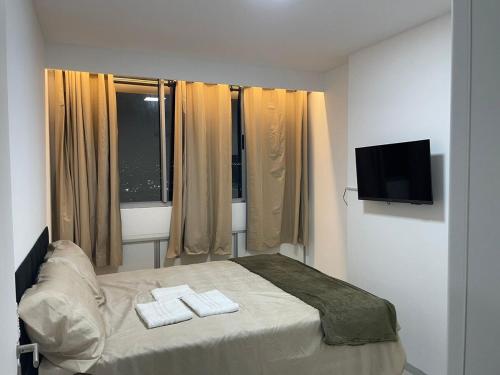 a bedroom with a bed with two towels on it at White Life in Caruaru