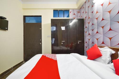 a bedroom with a red and white bed and a door at Hotel O Pragati Inn in Jaipur