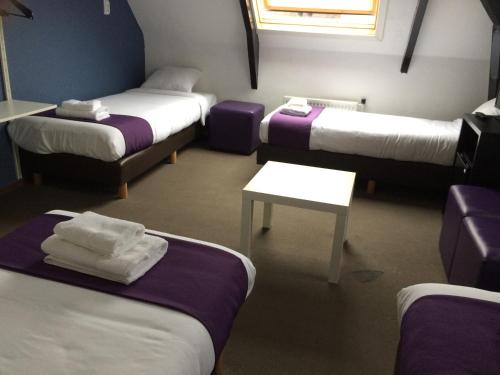 a room with three beds and a table in it at Hotel Bellington in Amsterdam