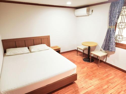 a bedroom with a bed and a table and a chair at 범어사 범어호텔 in Ch'ŏngnyong-dong