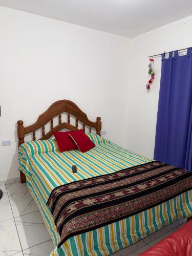 a bed with a colorful striped comforter in a bedroom at Runa Huasi in Tinogasta