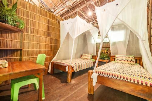 a room with two beds and a desk and a table at Alter Native Stay in Tapokreng