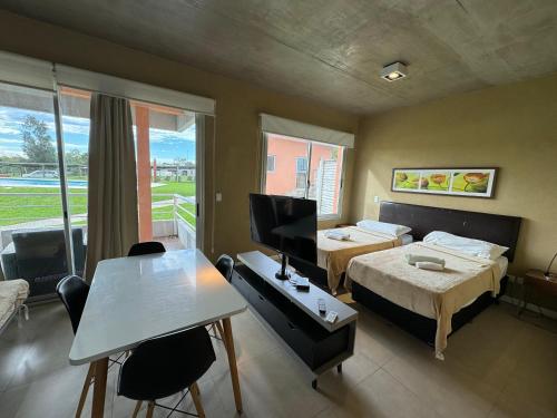 a room with two beds and a desk and a television at Lomas del Real Apart in Colonia del Sacramento
