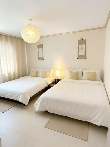 two beds in a room with white walls at Dazzlday in Seoul
