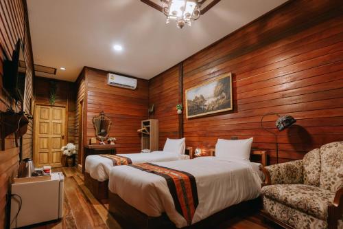 a hotel room with two beds and a couch at Chuchaiburi Sri Amphawa in Amphawa