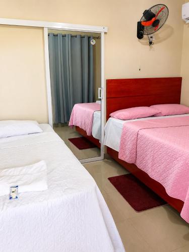 a room with two beds with pink and white sheets at Hotel los 4 Tesoros in Pedernales