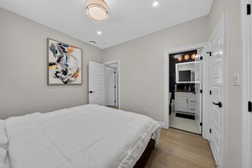 a white bedroom with a large bed and a bathroom at The Windsor Mainstay in Windsor