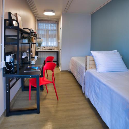 a room with two beds and a desk with two red chairs at Runway 1331 -ENLIGHT Youth Hostel in Hong Kong