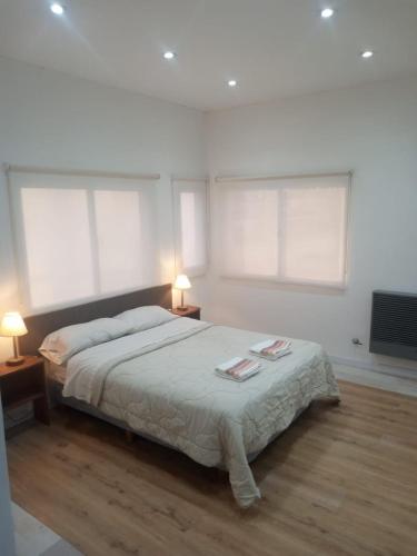a bedroom with a bed and two lamps and windows at El mejor descanso lll in Plottier