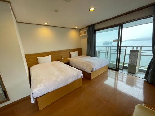 a hotel room with two beds and a large window at ウェルカムイン松島 in Matsushima