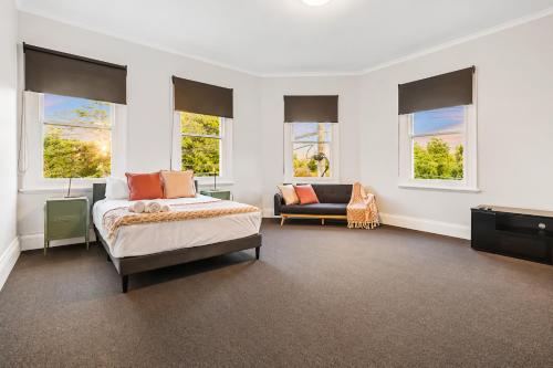 a bedroom with a bed and a couch and windows at Heritage-Style Boutique Hotel, Port Melbourne in Melbourne