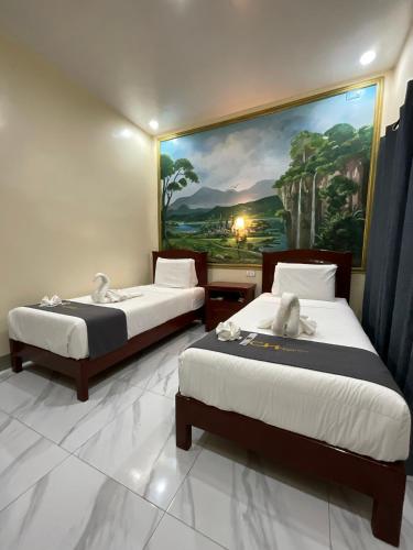 two beds in a room with a painting on the wall at Coastal Haven Resort in Siquijor