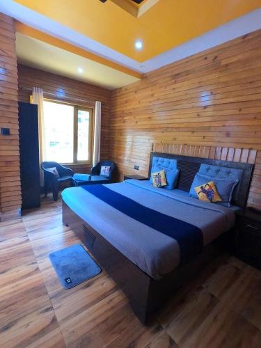 a bedroom with a large bed with a wooden wall at Bagwan Kainchi Stay in Bhowāli