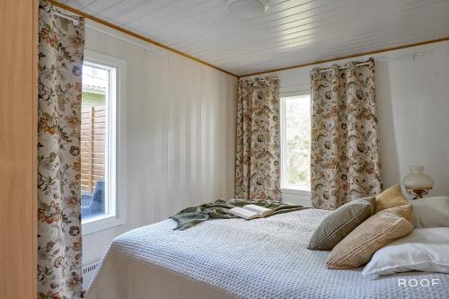 a bedroom with a bed and two windows at Villa Repovesi in Hillosensalmi